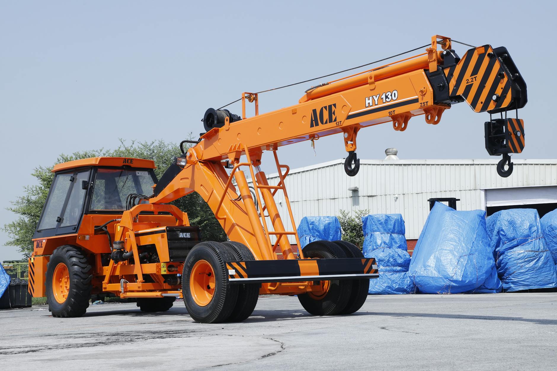 Pomarańczowy żuraw ACE HY130 na placu budowy w Faridabad w Indiach