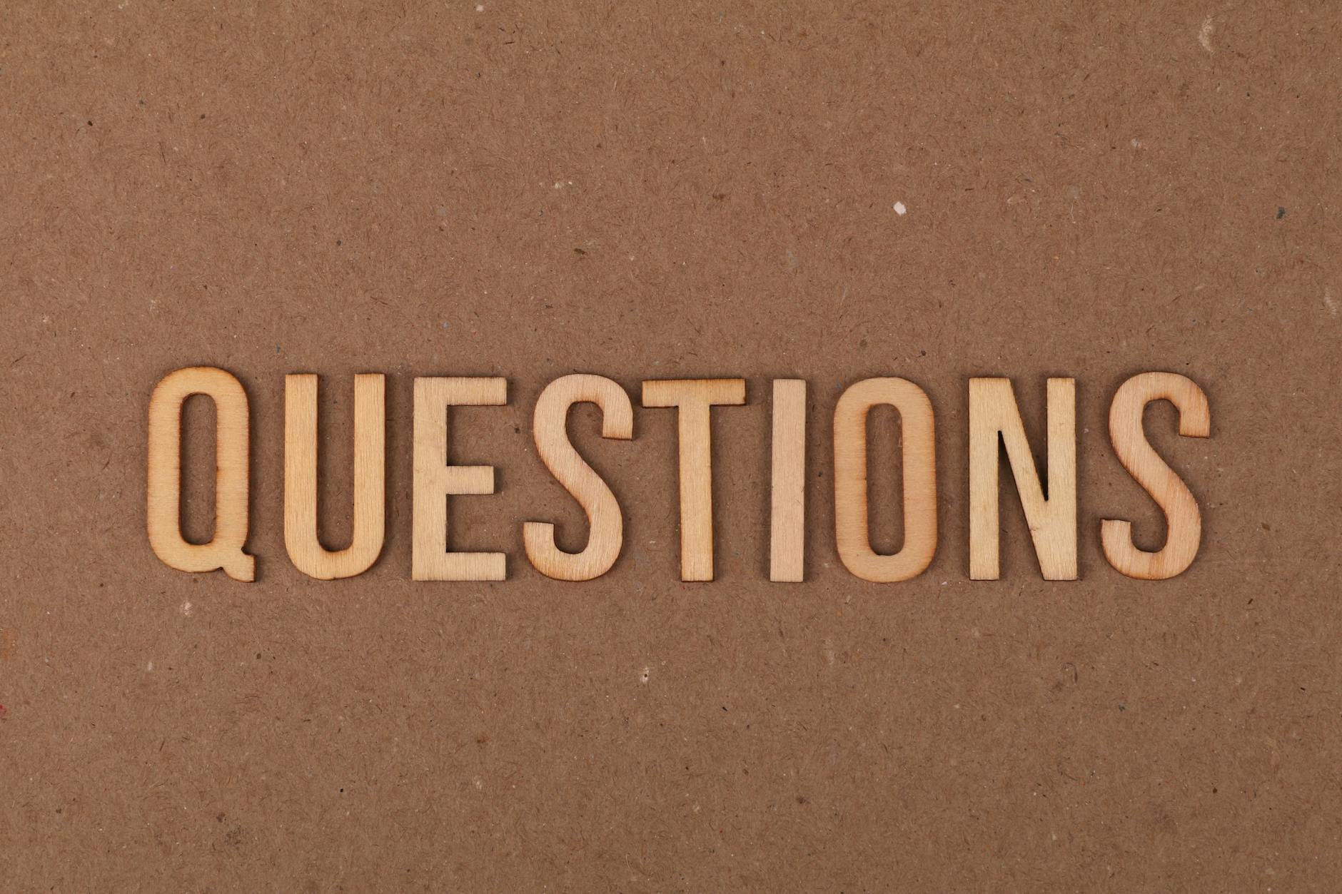 Drewniane litery układające się w napis QUESTIONS na kartonie