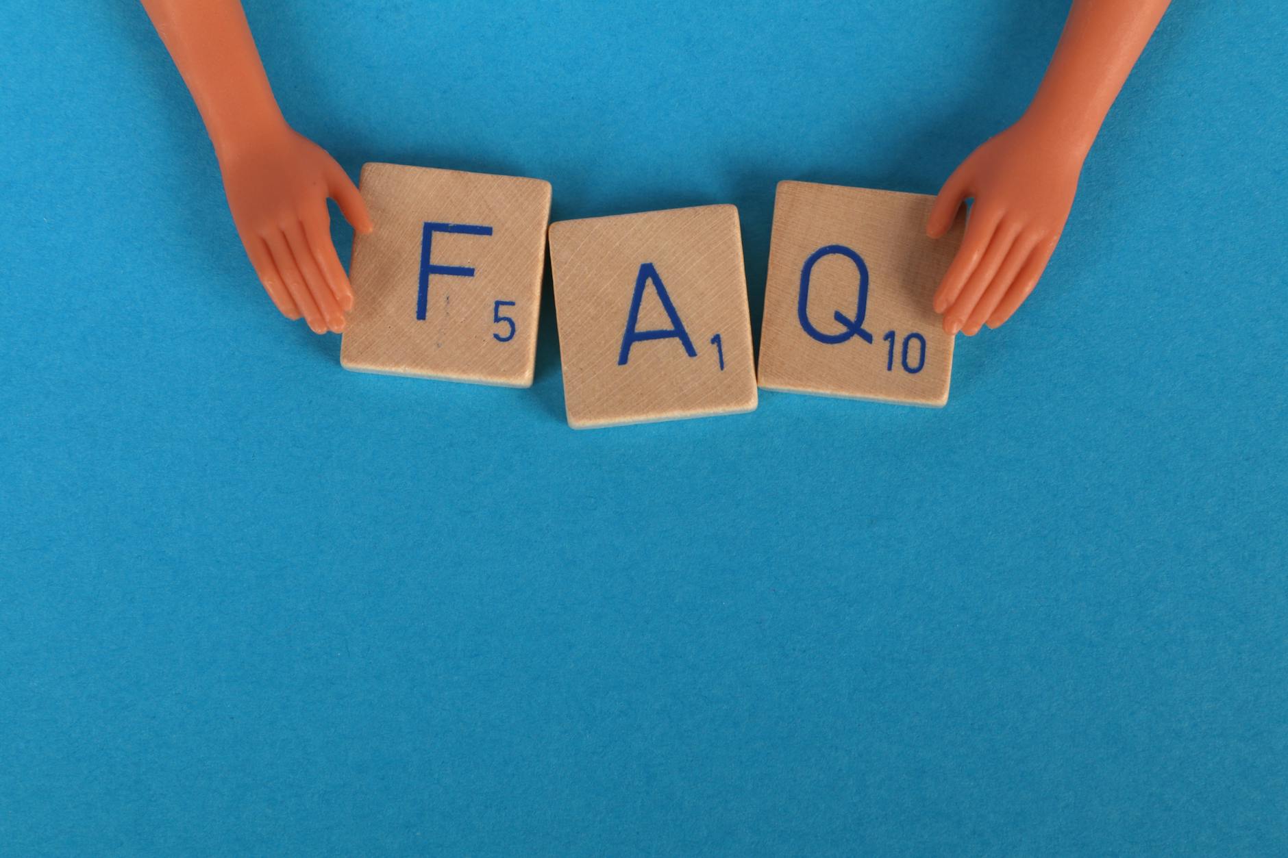 Kafelki FAQ i zabawkowe dłonie na niebieskim tle