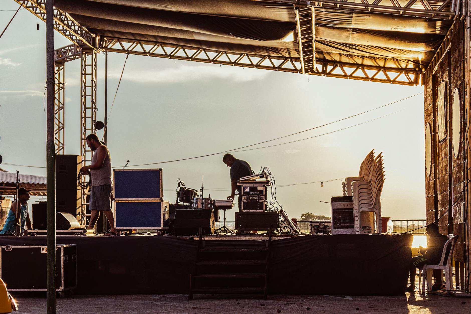 Muzycy przygotowują plenerową scenę o zachodzie słońca