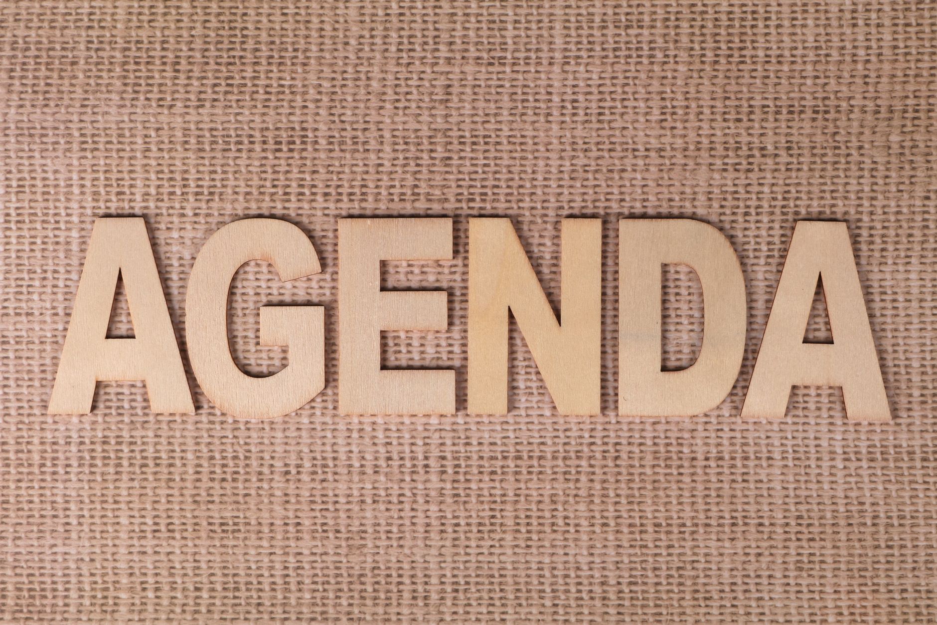 Drewniane litery tworzące słowo AGENDA na jutowym tle