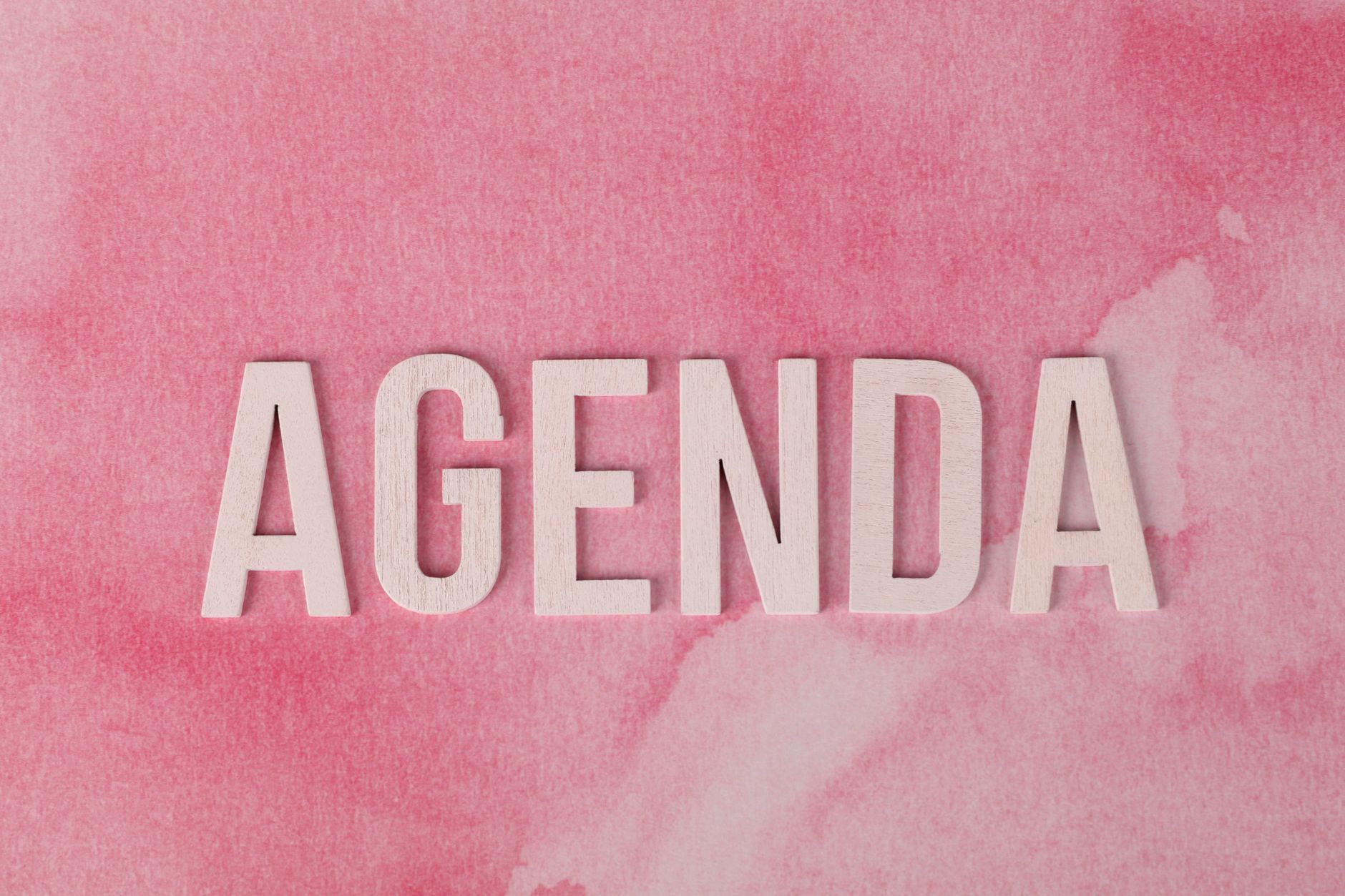 Drewniane litery układające się w napis agenda na różowym tle