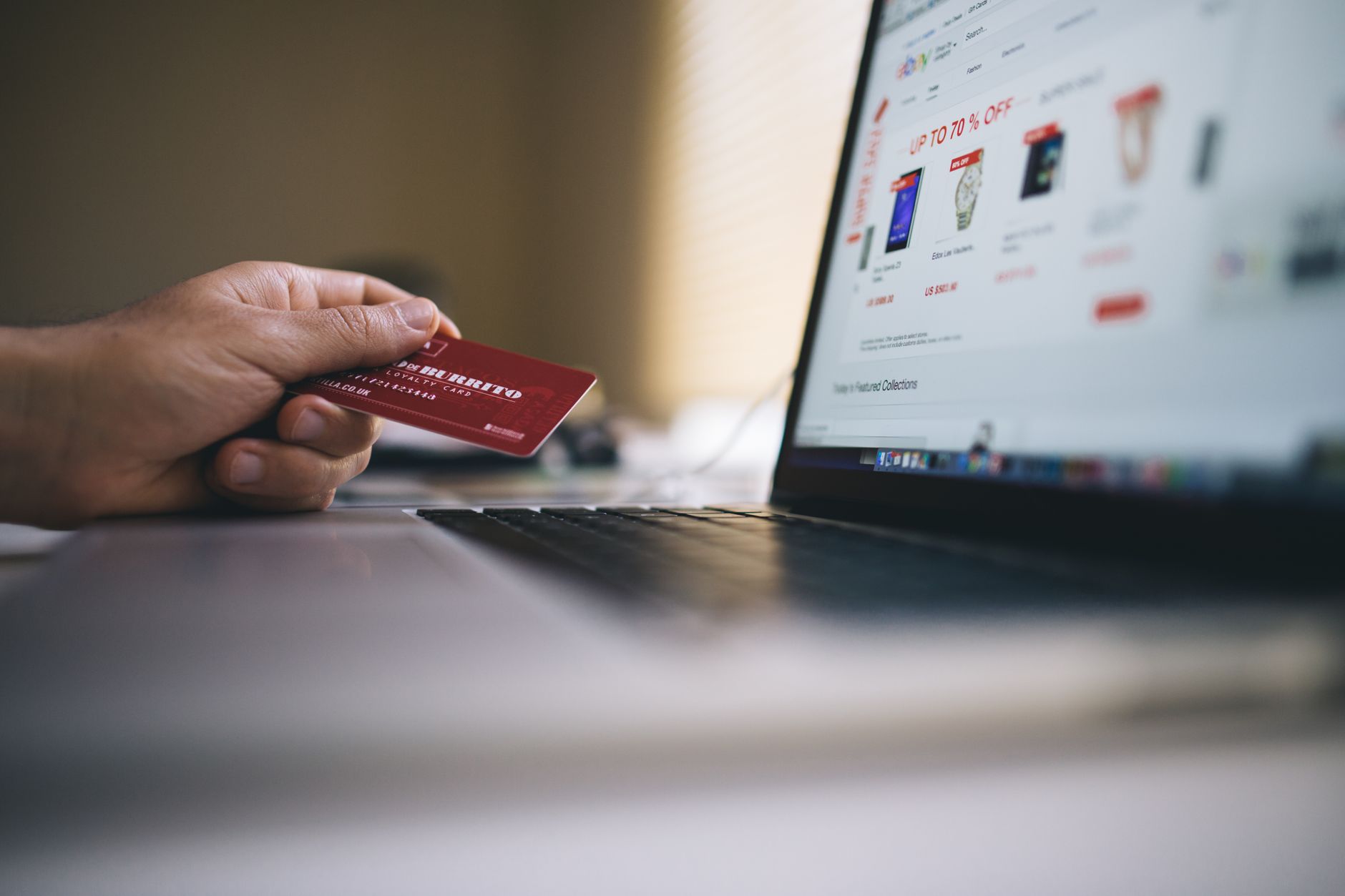 Osoba z kartą płatniczą przed laptopem podczas zakupu biletu online