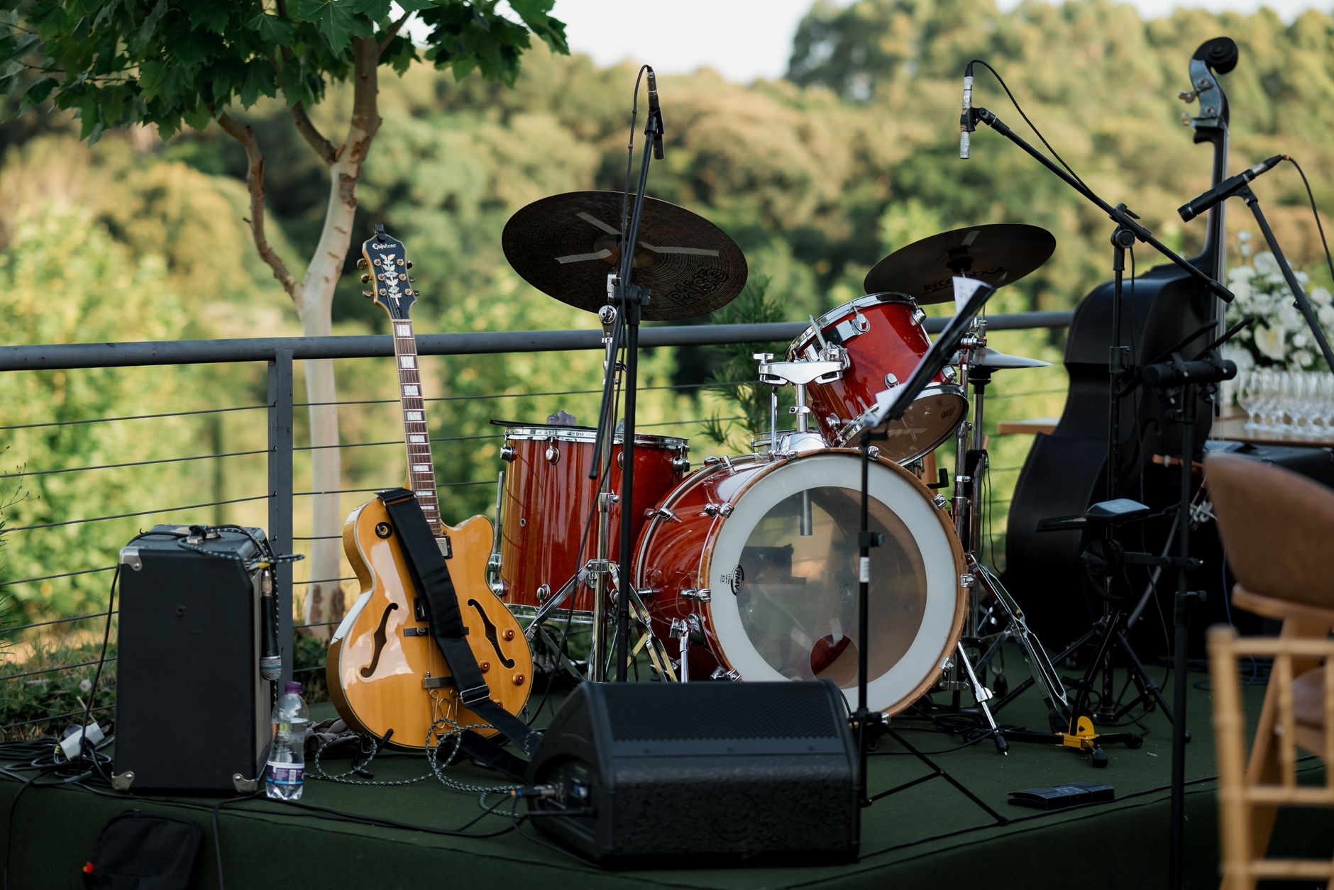 Plenerowa scena z perkusją, gitarą i wzmacniaczem wśród zieleni